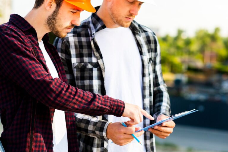 Construction engineers reviewing project plans on clipboard at a job site