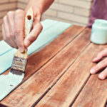 closeup of a young caucasian man painting an old wooden table with a brush