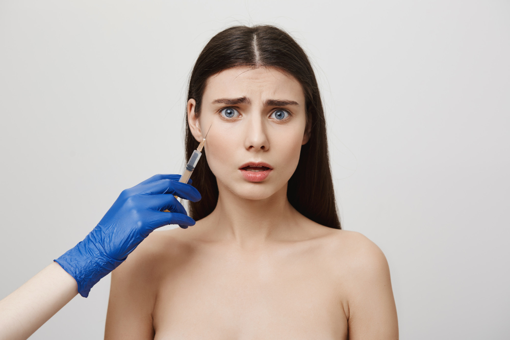 Worried woman receiving a botox injection near her eye.