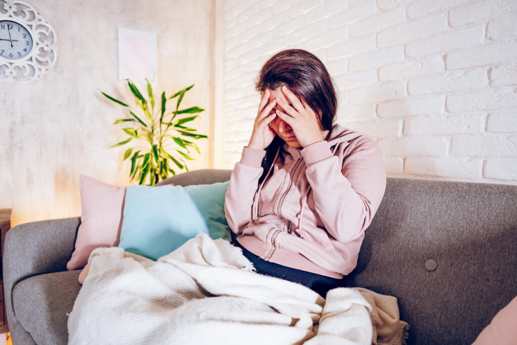 Woman-having-headache-while-sitting-on-sofa-at-home